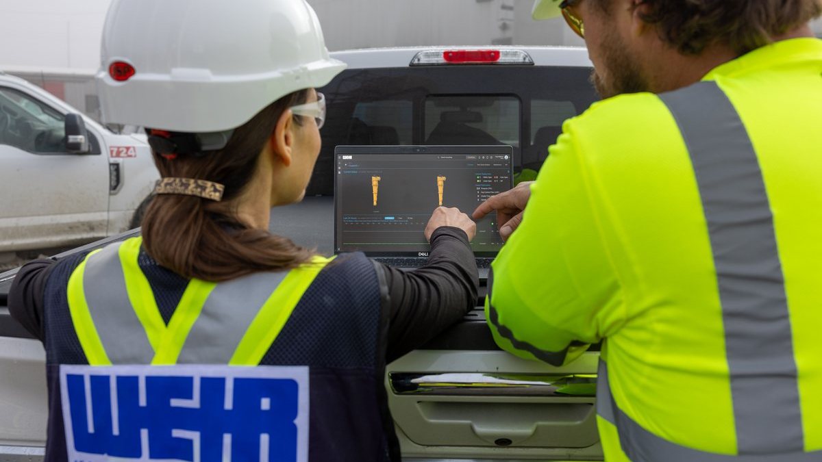 Sala de control de planta con visualización de digital twin y gráficos de rendimiento en pantallas